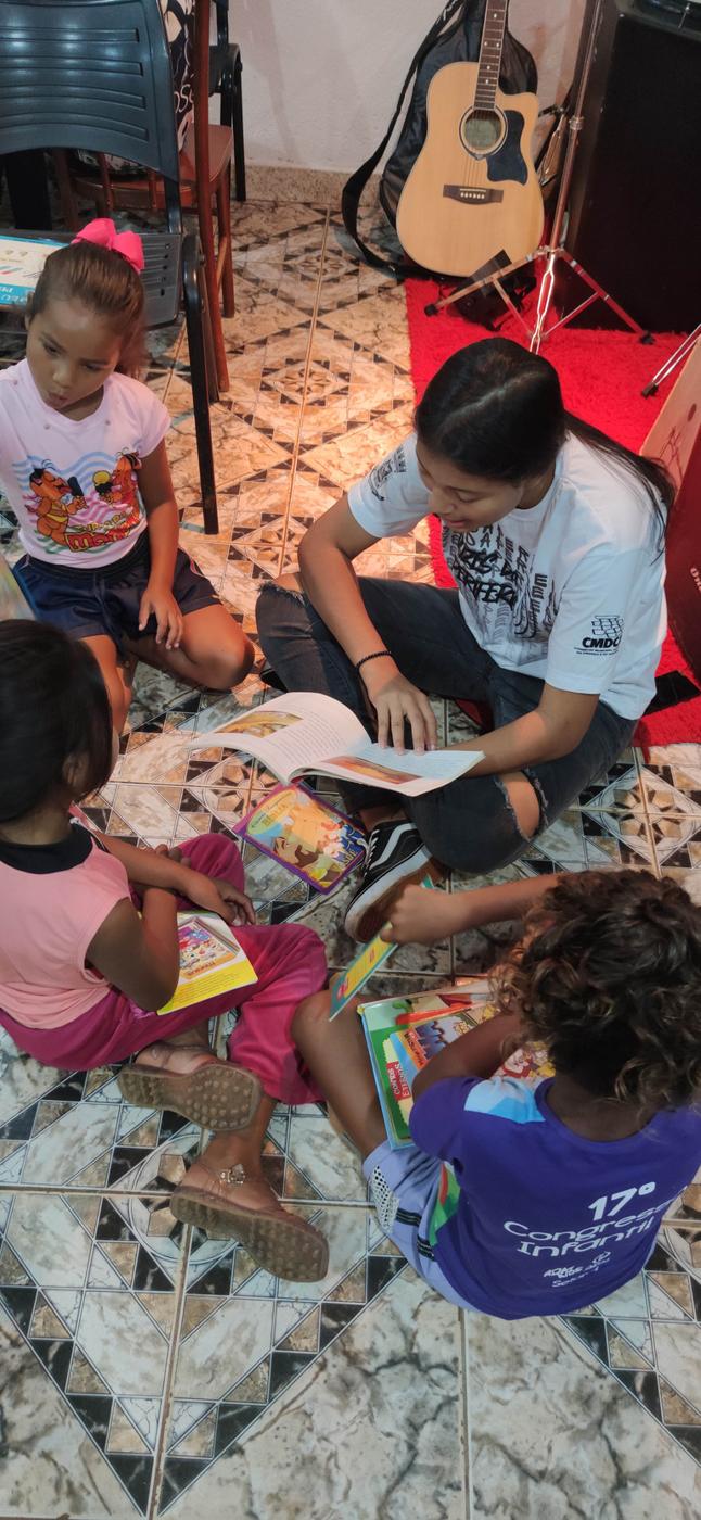 Educadora lendo um livro com crianças sentadas no chão